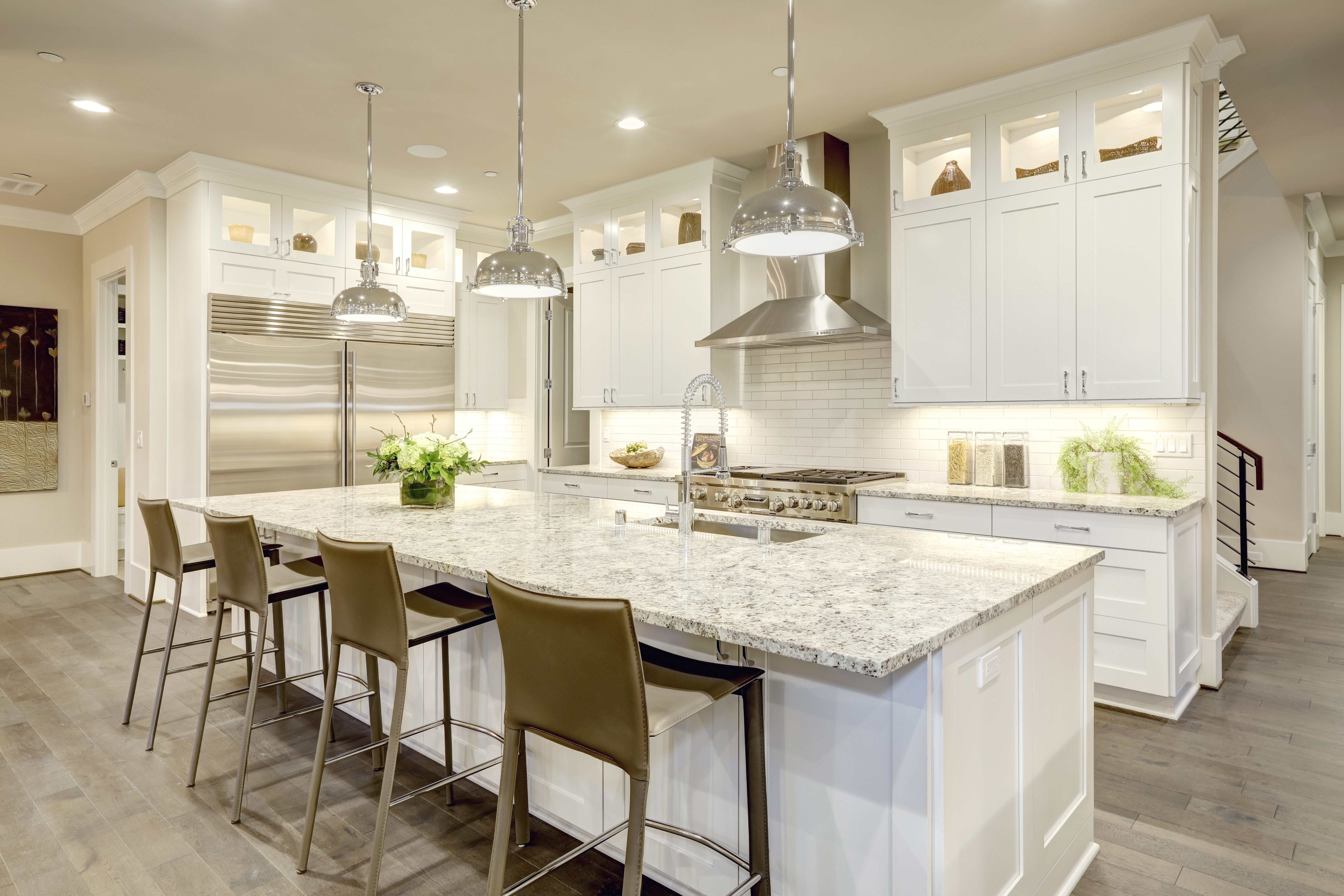 White kitchen design features large bar style kitchen island with granite countertop | Pierce Carpet Mill Outlet