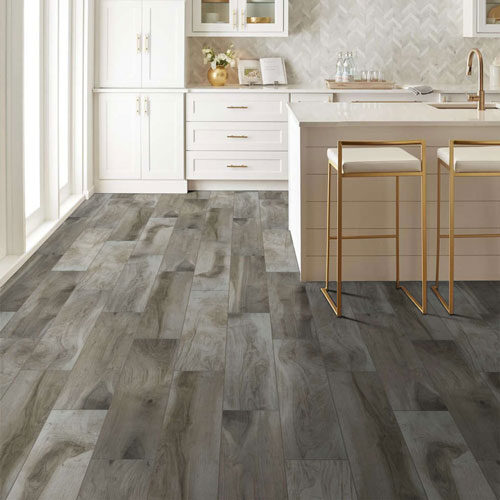 Modern kitchen with white cabinets, gold barstools, and gray-toned laminate flooring.