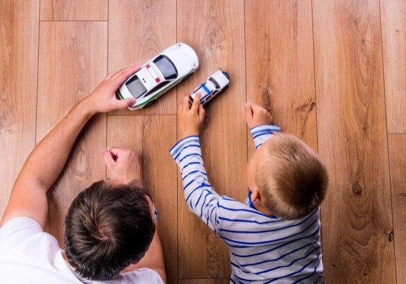 Kid playing with father laying on laminate flooring | Pierce Carpet Mill Outlet
